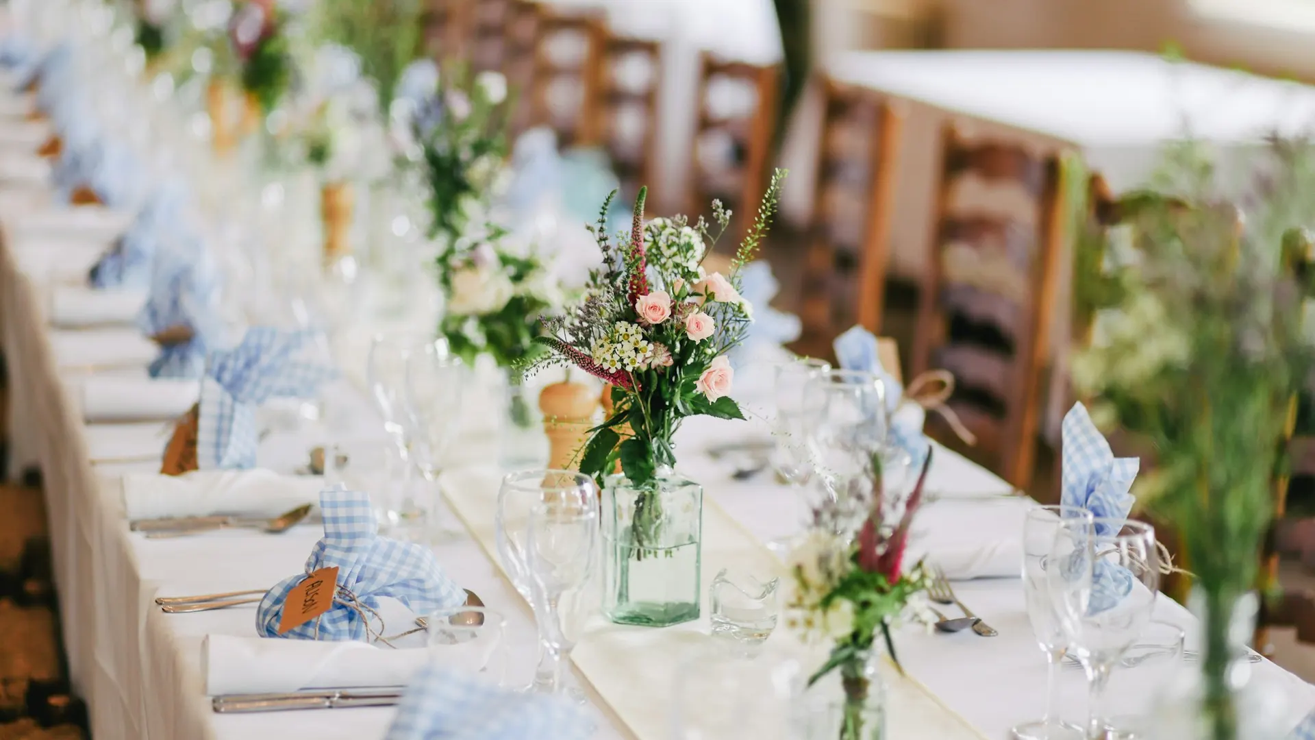 Open lawn ceremony setting with wooden chairs facing a simple floral arch.